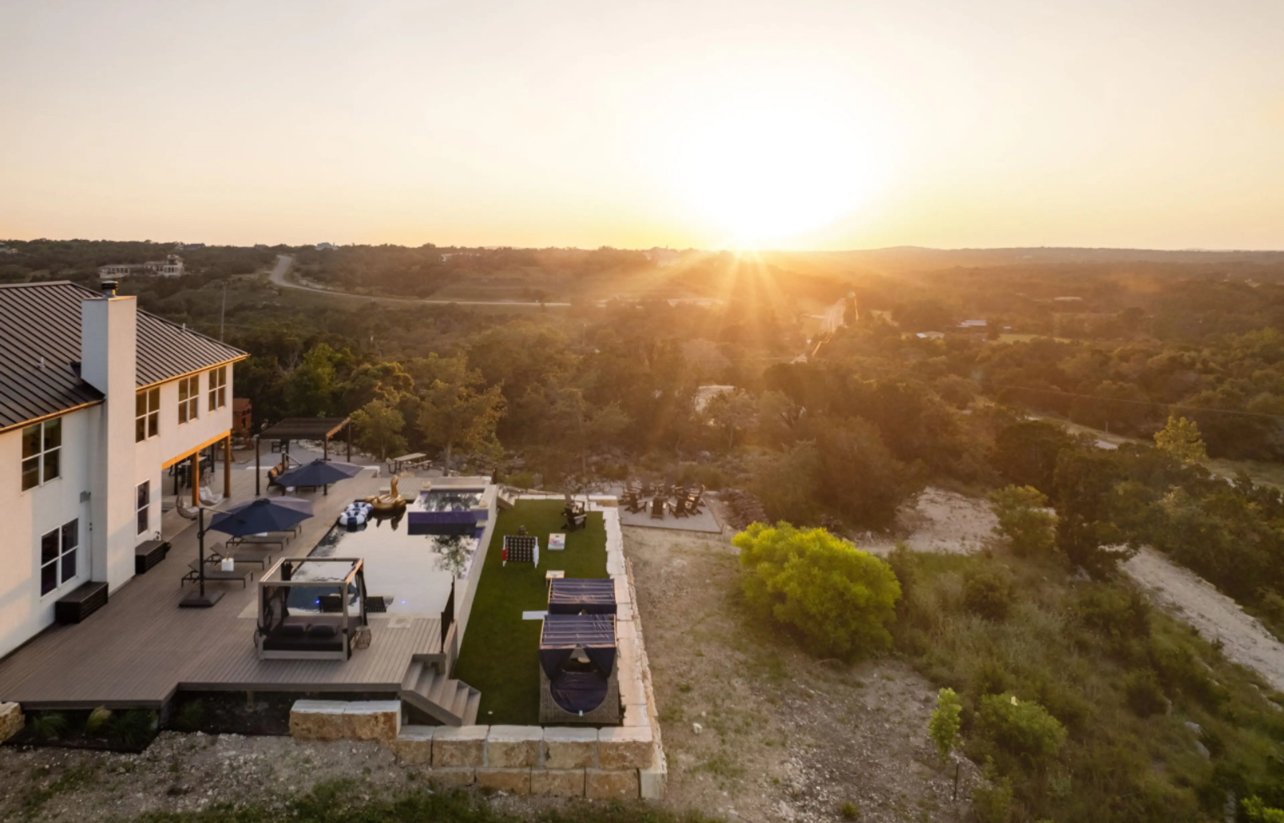 outdoor custom hardscape patio with stone retaining walls, artificial turf, and wood deck